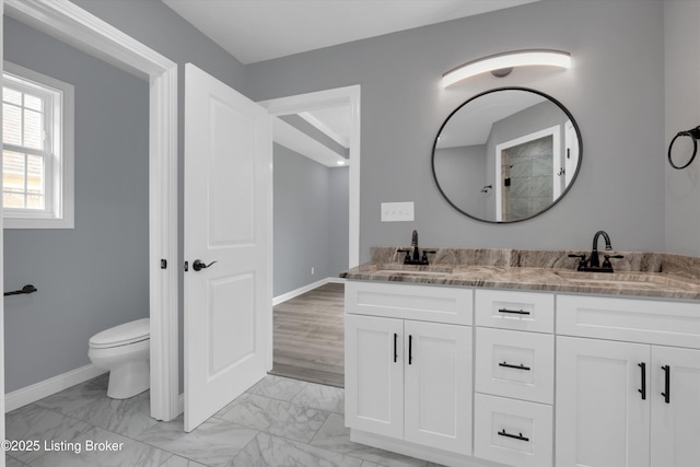 bathroom featuring double vanity, toilet, marble finish floor, and a sink