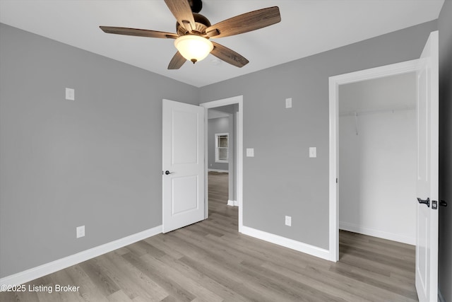 unfurnished bedroom featuring baseboards, wood finished floors, a ceiling fan, and a closet