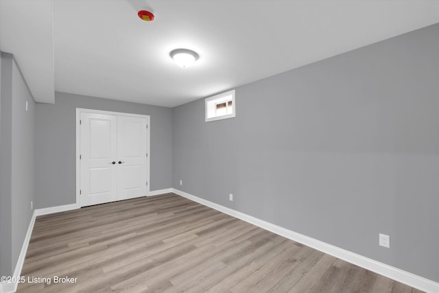 unfurnished bedroom featuring wood finished floors, a closet, and baseboards