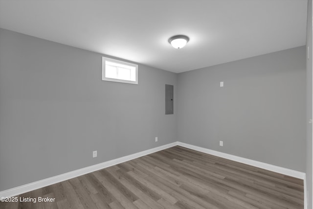spare room with wood finished floors, electric panel, and baseboards