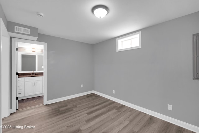 unfurnished bedroom featuring baseboards, visible vents, and wood finished floors