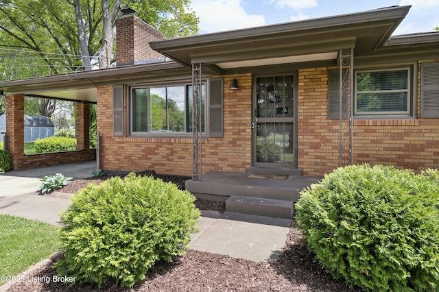 property entrance featuring a chimney and brick siding