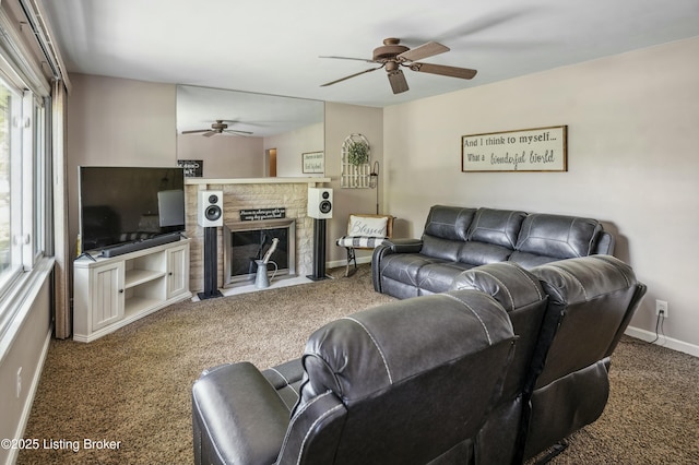 living room featuring baseboards, a ceiling fan, a fireplace with flush hearth, and carpet