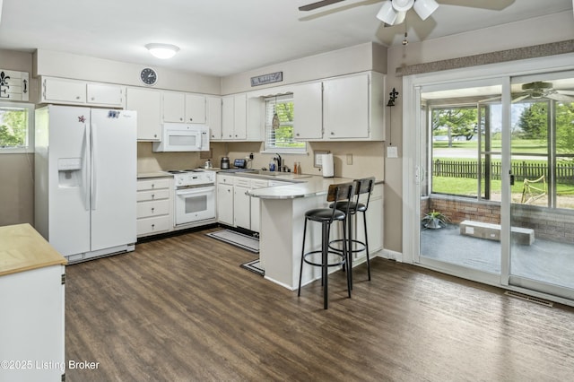 kitchen featuring white appliances, a ceiling fan, dark wood-style floors, and a peninsula