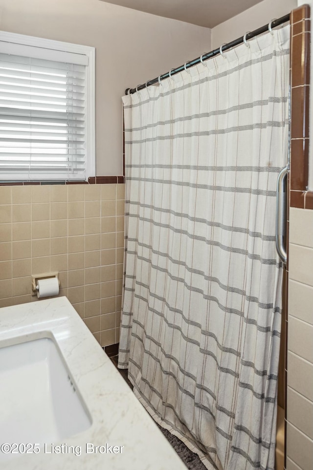 full bathroom featuring a shower with curtain, tile walls, and a sink