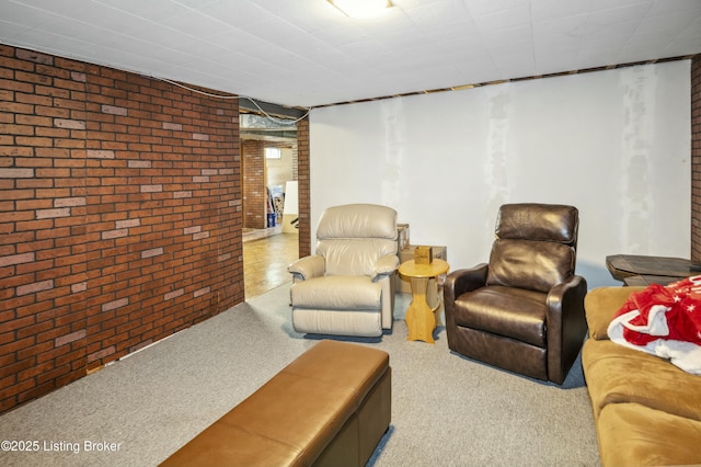living area featuring carpet flooring and brick wall