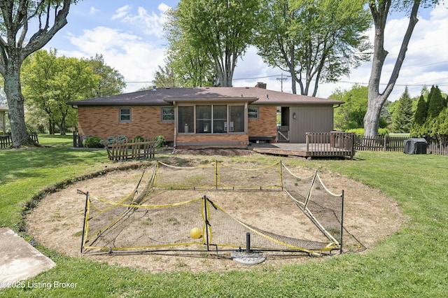 back of house featuring a lawn, a vegetable garden, a wooden deck, and a sunroom
