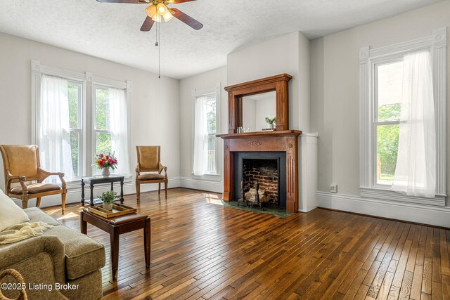 309 W Madison St, La Grange, KY 40031 - living area featuring hardwood / wood-style flooring, a textured ceiling, ceiling fan, a fireplace with flush hearth, and baseboards