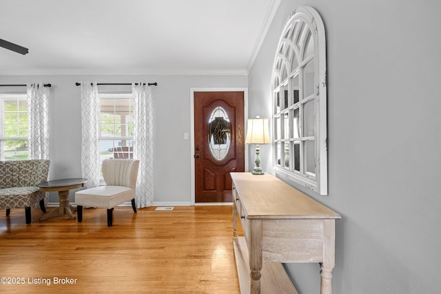 foyer featuring baseboards, visible vents, light wood-style floors, and crown molding