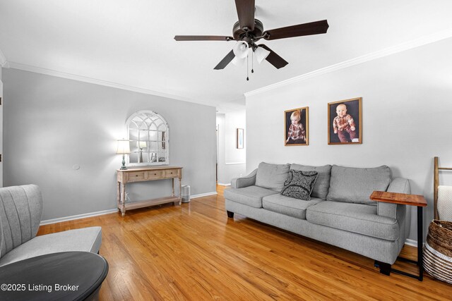 living area featuring baseboards, light wood-style flooring, ceiling fan, and crown molding