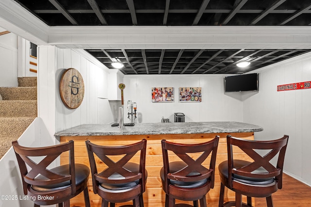 bar with wood finished floors, wet bar, and stairs