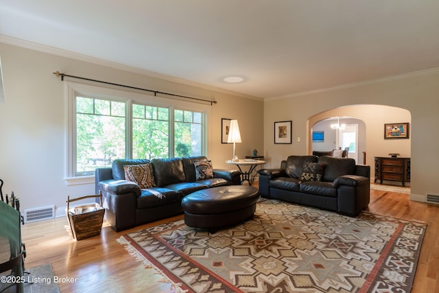 living area with arched walkways, visible vents, wood finished floors, and plenty of natural light