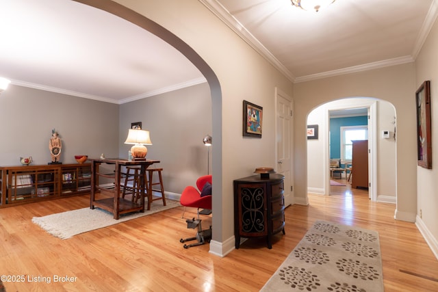 hall featuring wood finished floors, baseboards, ornamental molding, and arched walkways