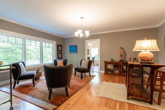 living area featuring a chandelier, baseboards, ornamental molding, and wood finished floors