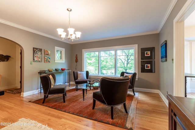 sitting room featuring ornamental molding, light wood finished floors, arched walkways, and a notable chandelier