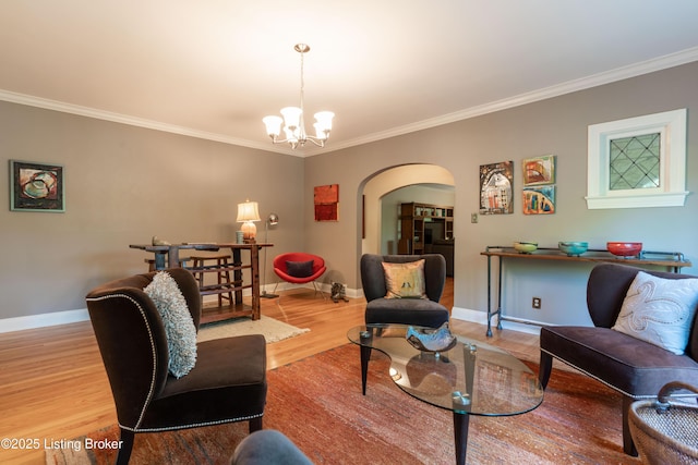 living area featuring wood finished floors, ornamental molding, a notable chandelier, and arched walkways