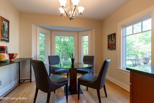 dining area featuring a chandelier, baseboards, and light wood-style floors