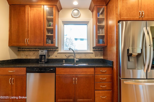 kitchen featuring appliances with stainless steel finishes, backsplash, glass insert cabinets, and a sink