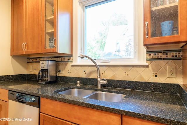 kitchen featuring a sink, brown cabinets, decorative backsplash, dark stone countertops, and dishwasher