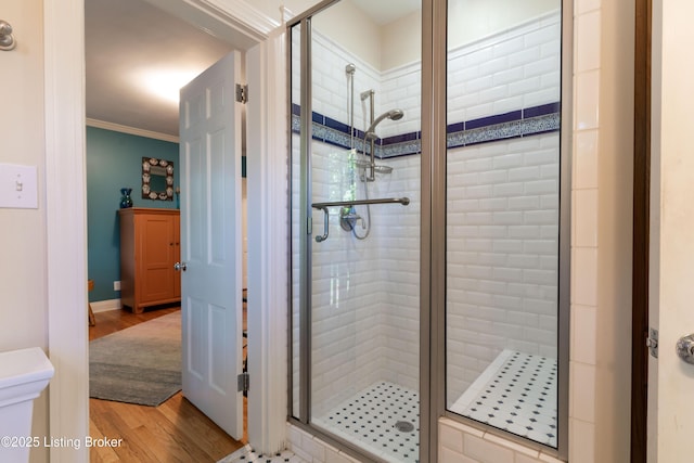 bathroom featuring wood finished floors, a shower stall, and ornamental molding