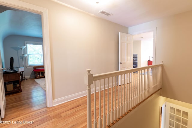 corridor featuring an upstairs landing, visible vents, light wood-type flooring, and baseboards