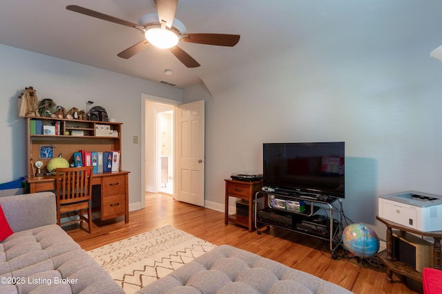 living room featuring a ceiling fan, visible vents, wood finished floors, and baseboards