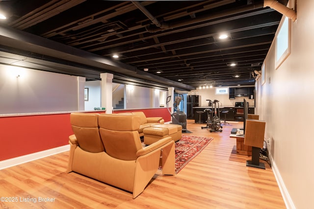 cinema room featuring light wood-style floors, bar, and baseboards
