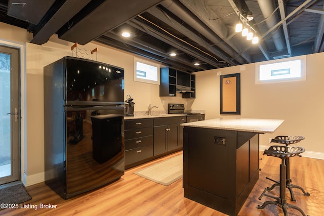 kitchen featuring black appliances, light wood-style floors, open shelves, and a sink