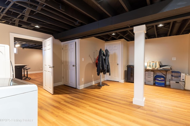 finished below grade area with baseboards, light wood-type flooring, and stacked washer / dryer