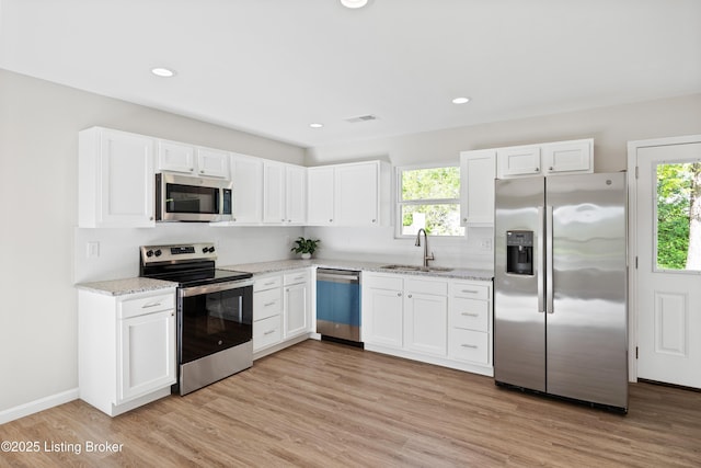 kitchen with a sink, stainless steel appliances, white cabinetry, and visible vents
