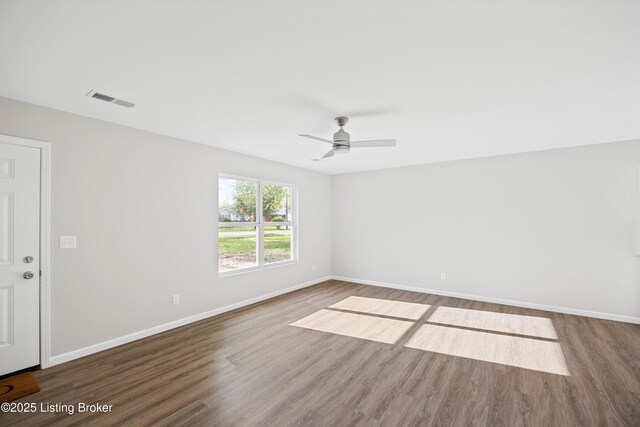 spare room featuring baseboards, wood finished floors, and visible vents