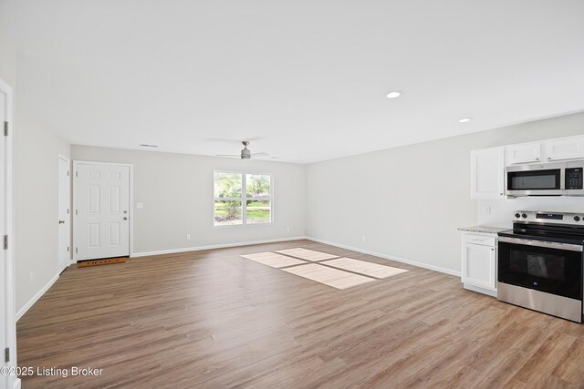 kitchen featuring white cabinets, stainless steel appliances, ceiling fan, and light wood-type flooring