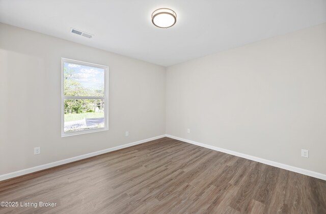 unfurnished room featuring visible vents, baseboards, and wood finished floors