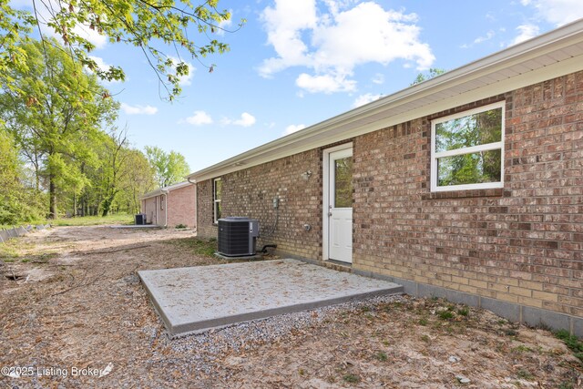 exterior space featuring brick siding, central AC, and a patio area