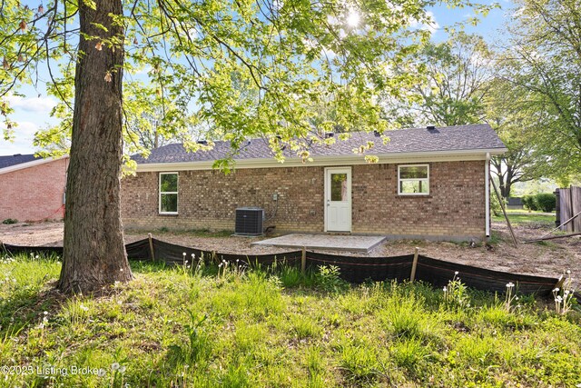 back of property featuring brick siding, central AC unit, and a shingled roof