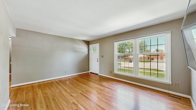 empty room with baseboards, visible vents, and light wood finished floors