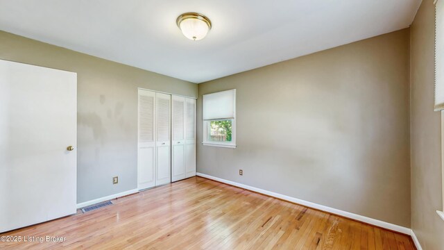 unfurnished bedroom with visible vents, light wood finished floors, baseboards, and a closet