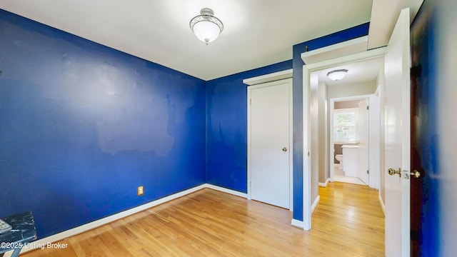 unfurnished bedroom featuring baseboards, wood finished floors, and a closet