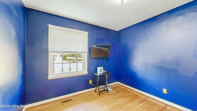 unfurnished room with baseboards, wood finished floors, and visible vents