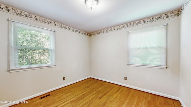 empty room with baseboards, wood finished floors, and visible vents