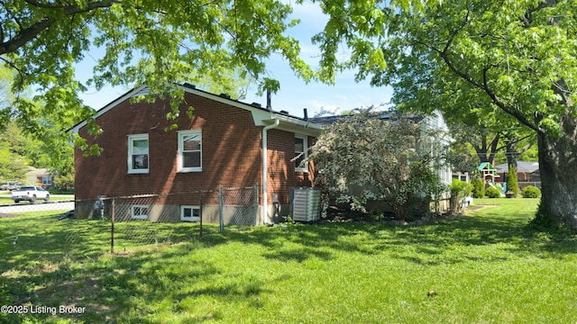 view of side of home with a lawn, central AC unit, fence, and brick siding
