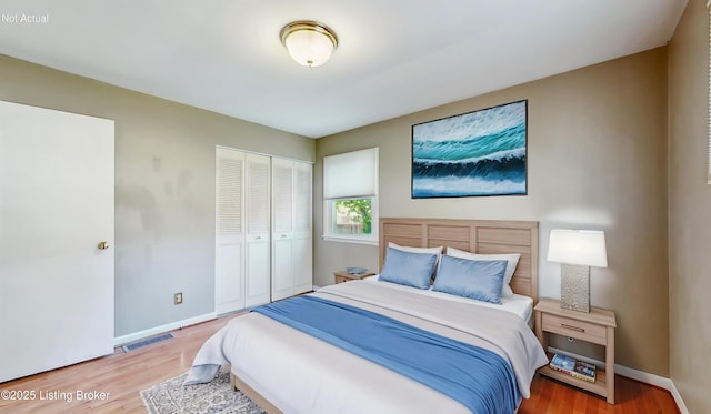 bedroom featuring visible vents, baseboards, wood finished floors, and a closet
