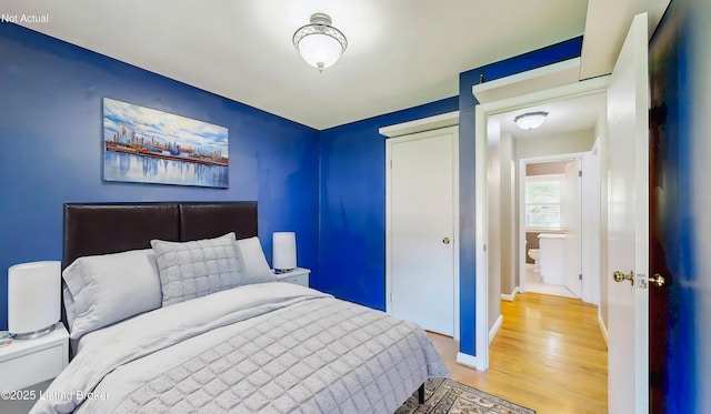 bedroom featuring baseboards, light wood finished floors, and a closet