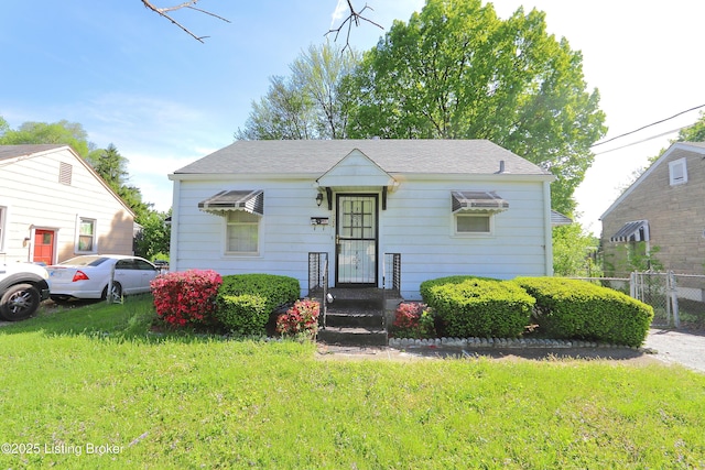 bungalow featuring a front yard, a shingled roof, and fence