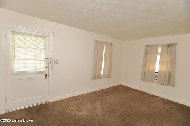 unfurnished room featuring baseboards and dark carpet