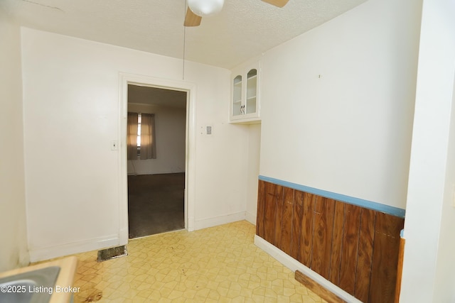 unfurnished room featuring a ceiling fan, baseboards, a textured ceiling, and light floors