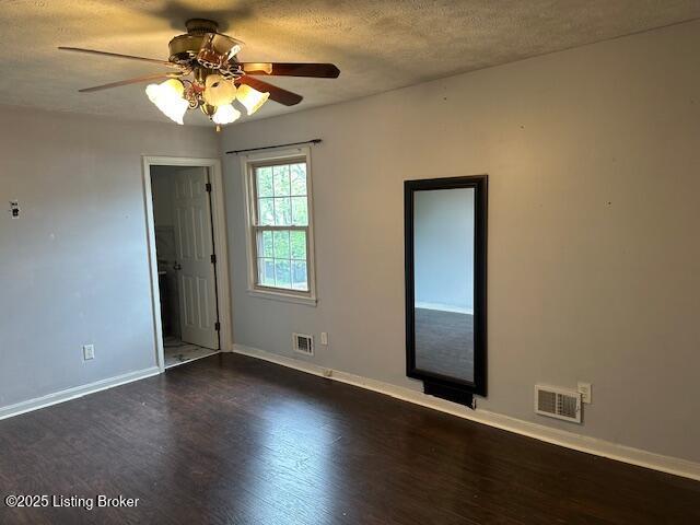 empty room featuring dark wood finished floors, visible vents, and baseboards