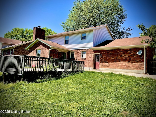 rear view of property with a deck, a yard, and brick siding