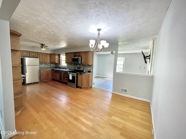 kitchen with stainless steel appliances, a sink, visible vents, a notable chandelier, and a textured ceiling