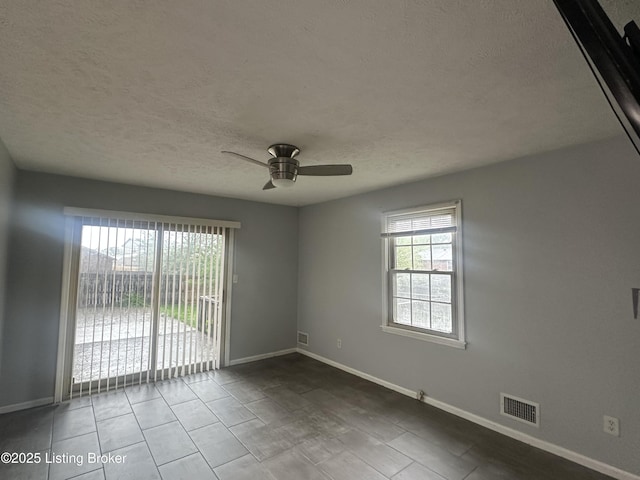 empty room with baseboards, visible vents, a ceiling fan, and a textured ceiling